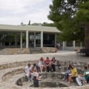 A group sits on a stone circle in front of a building.