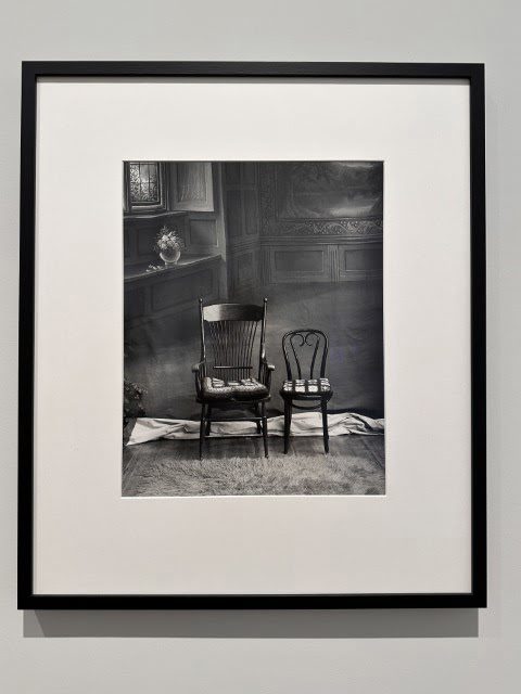 A black and white painting hangs in a picture frame on a piece of furniture inside the room.
