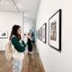 A person is admiring a painting at an art gallery during an indoor art exhibition and vernissage.