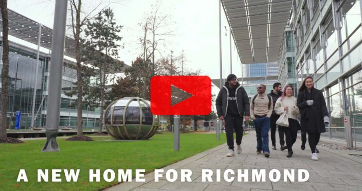 People are standing in front of a building surrounded by a tree, grass, and plants in the city skyline with a sign announcing a new home for Richmond.